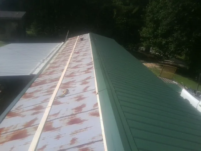 Old rusted panels beside newly installed green metal roofing — Wind Damage Roof Repair by Roofing Brothers in Idledale