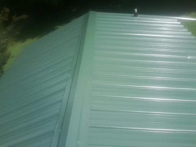 New green metal panels meeting at the ridge of a roof — Flat Roof Repair work by our crew in Idledale
