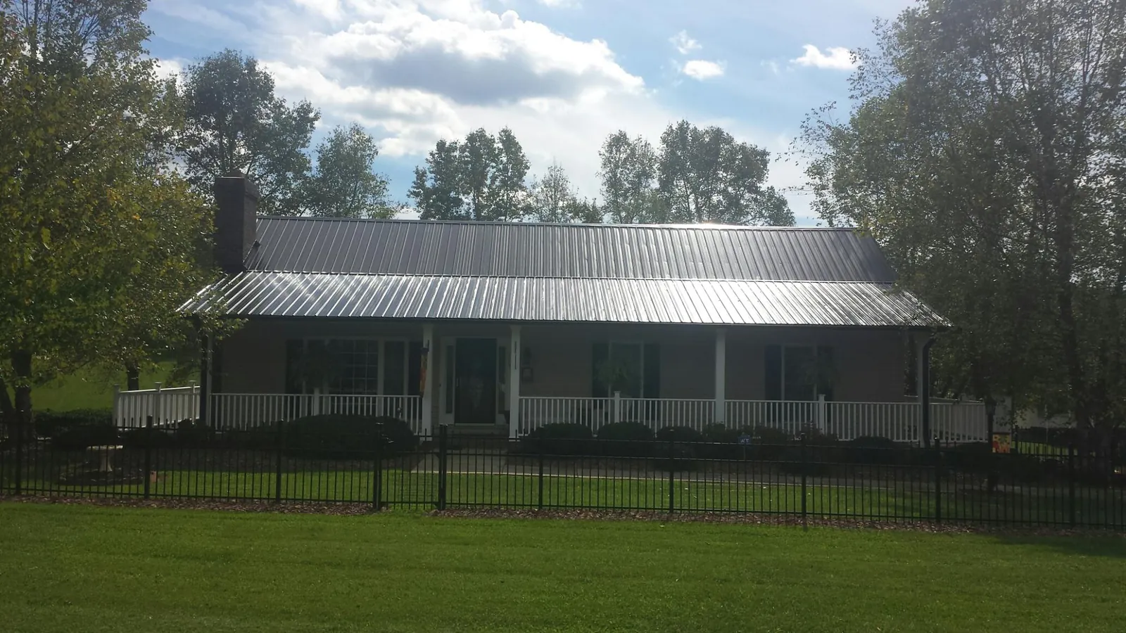 Gray metal roof on a brick ranch with a full width front porch — Gutter Guard Installation work by our crew in Idledale
