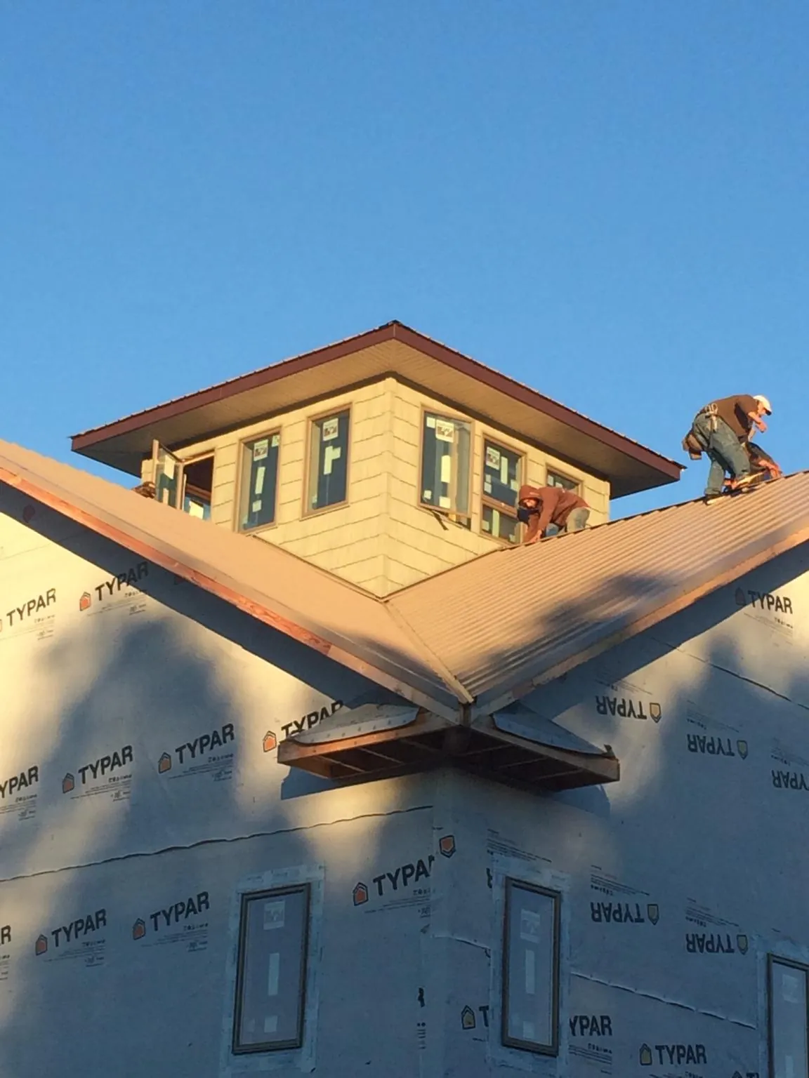 Roofers working around a rooftop cupola on a new metal roof at sunset — Roof Waterproofing in Idledale by Roofing Brothers